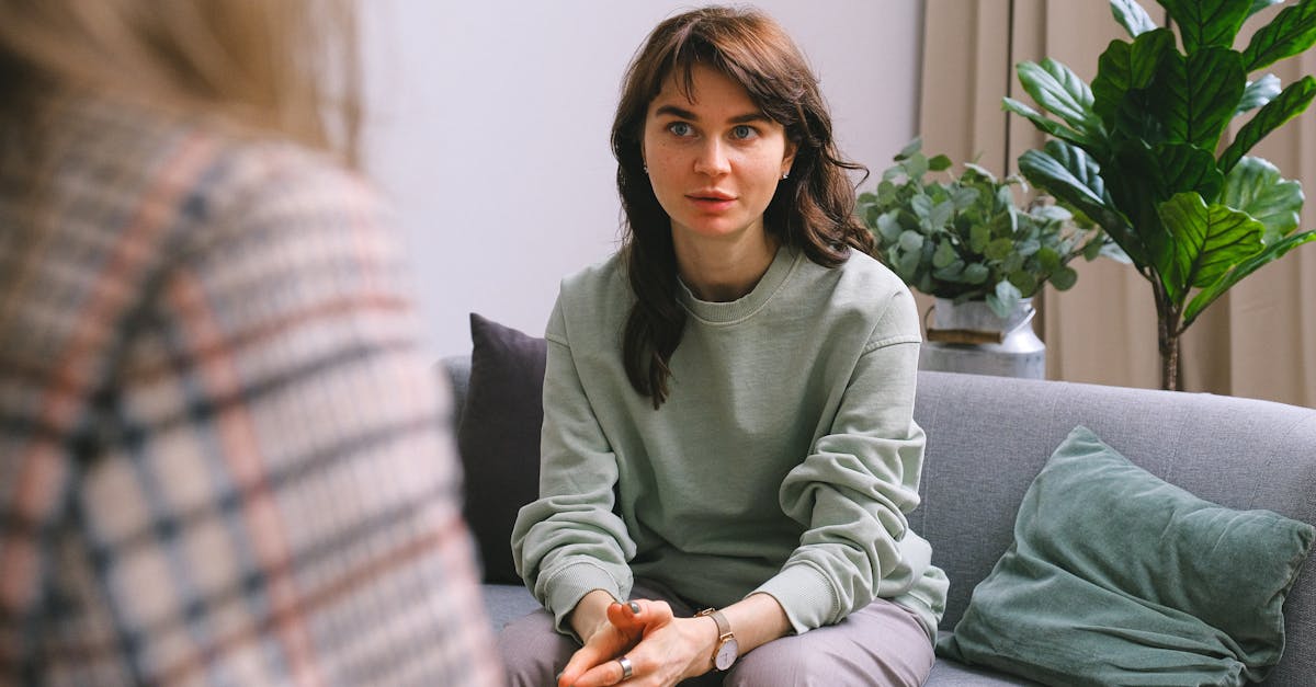 A focused woman during a therapy session, seated on a sofa indoors.